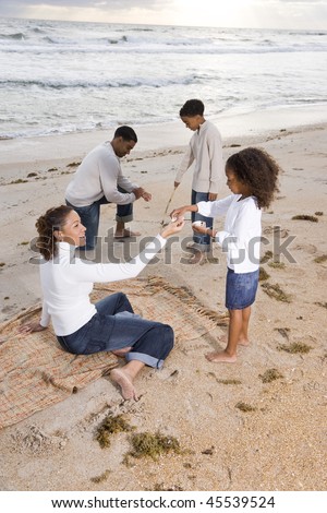 Happy African-American family with two children playing together on beach