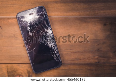 Smartphone mobile with a broken screen. Background wood