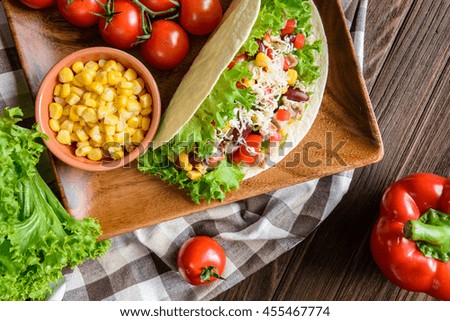 Traditional Mexican tacos with chicken meat, beans, lettuce, corn, onion, tomato and cheese