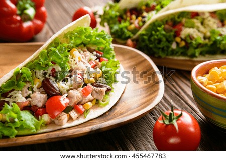 Traditional Mexican tacos with chicken meat, beans, lettuce, corn, onion, tomato and cheese