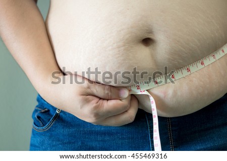 Women overweight checking out her body fat with measuring tape or line tape Royalty-Free Stock Photo #455469316