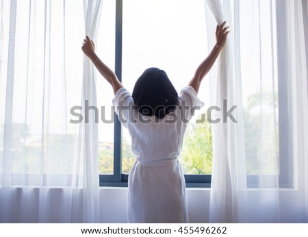 Woman, wake up and open the curtains in the morning to get fresh air. Royalty-Free Stock Photo #455496262