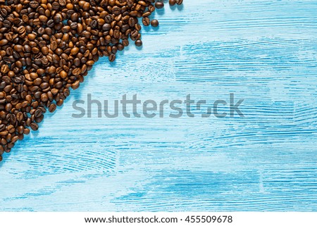 Scattered roasted coffee beans in corner of blue wooden background. Top view. Flat lay. Close up