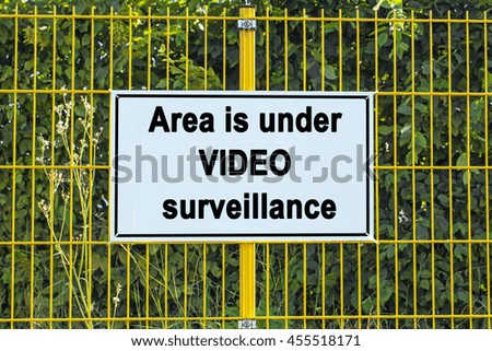 Area is under video surveillance text  on Warning Sign on yellow metal grille fence