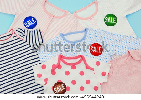 Baby clothes and tags on color background. Sale concept