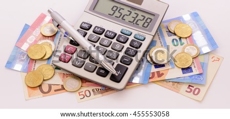 Many Euro banknotes and calculator laying on table