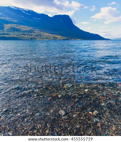 Summer picture of norwegian fjord with water and beach pebbles, Norway, Lofoten Islands