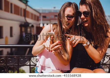young pretty woman posing in the street with phone, outdoor portrait, hipster girls, sisters, chic, tablet, internet, using smartphone, close-up fashion model, post in instagram, facebook,selfie, USA Royalty-Free Stock Photo #455568928