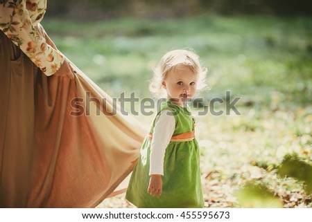 little daughter holding  skirt her  mother