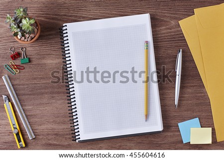 Office Desk Table with a Blank Tablet, Paper, Ruler, Pen, Notebook, Envelope, Plant Pot, Clips and Supplies. Workplace. Top View on a Wooden Background with Copy space for text or Image