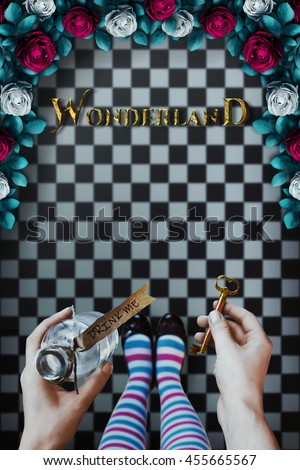 Alice in wonderland. Background. A key and a potion in hands against a  chess floor, Red  roses and white roses