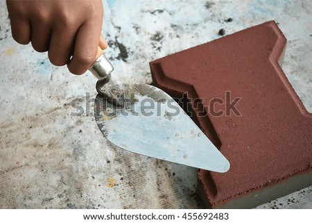 Human hands pressing wet cement in metal block to make concrete block