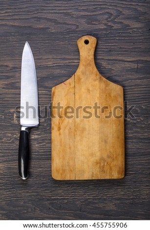 Empty chopping board with a knife on a distressed grunge wooden table in a rustic kitchen,