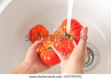 Female hands washing tomatoes in kitchen sink