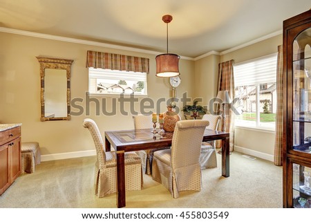 Dining area with beige walls and old wooden furniture. Also carpet floor