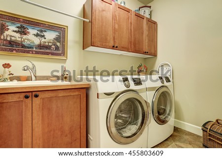 Laundry room with modern appliances, brown vanity cabinet with drawers.