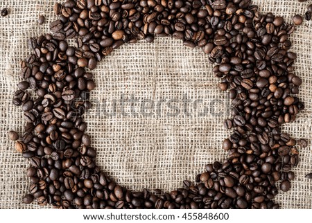 the coffee grains scattered on a table near a cup with coffee