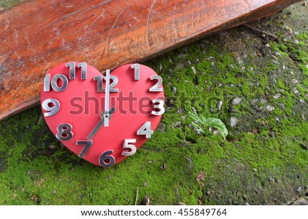red heart clock on floor with wood and green moss