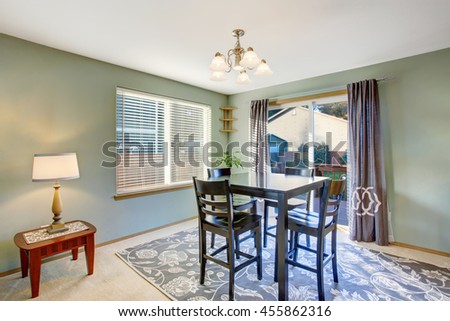 Dining area in green tones with black table set and carpet floor