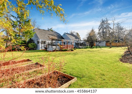 Large back yard with grass, covered wooden deck and grass. View from garden