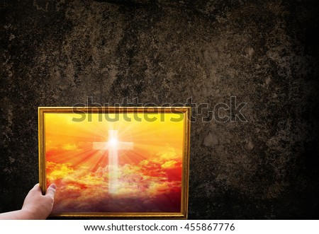 Hand hold picture frame of crucifix or cross on golden heavently sky on dark grunge wall