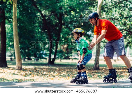 Father teching son roller skating in park
