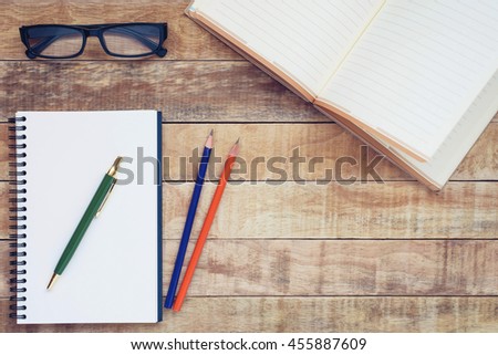 Notebook and pen with glasses on wood background