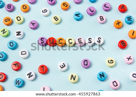 Success word composed of abc colorful letters on blue desk table background. 
Inspiration picture motive to achieve success in life, business, relationships, be a winner of competition and team leader