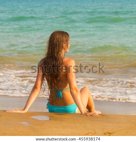 Woman sitting on seacoast in the surf line. Summer holidays concept.
