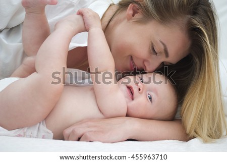 Mother and baby daughter on bed