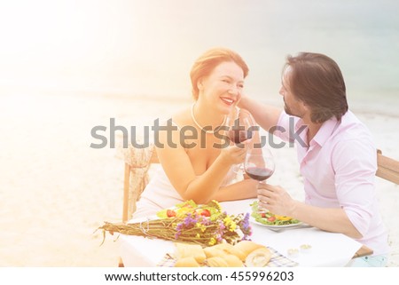 Toned picture of happy couple spending free time all together in restaurant or cafe. Handsome man and beautiful woman having lunch with red wine. People laughing, hugging and kissing.