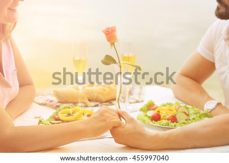 Closeup toned picture of two people man and woman holding hands. People in love resting in restaurant or cafe near by sea.