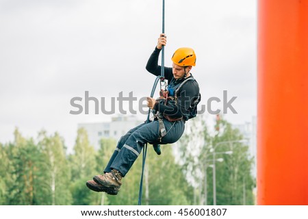 Industrial climber in uniform and helmet rises Royalty-Free Stock Photo #456001807