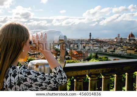 Woman stands on the bridge and looks on the city through the glasses