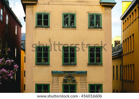 A picture of yellow house with green windows