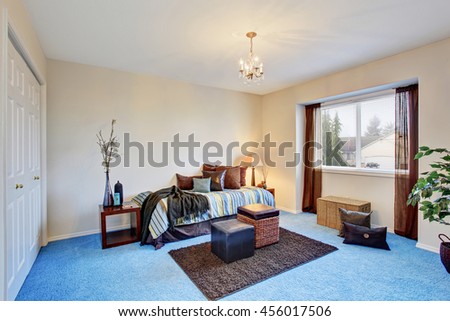 Modern bedroom with blue carpet floor and dark brown curtains