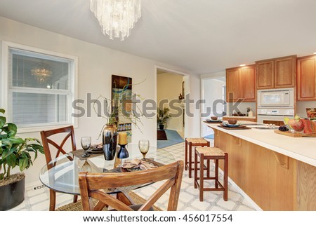 Dining area with glass table and tile floor connected to kitchen