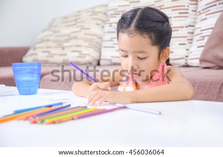 Portrait of cute asian little girl Thai painting the color at home shallow depth of field