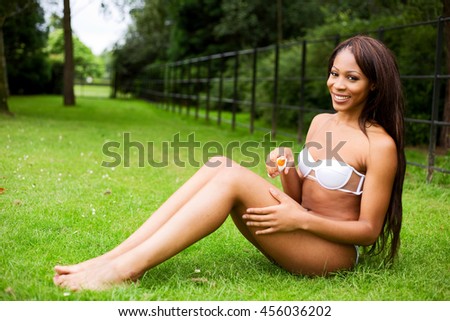 young woman in the park using a sun protection spray cream