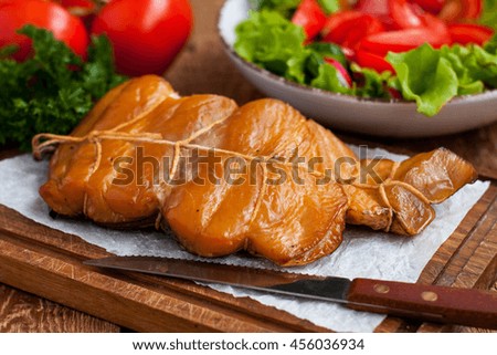 Smoked white fish fillet on wooden serving board with vegetable salad