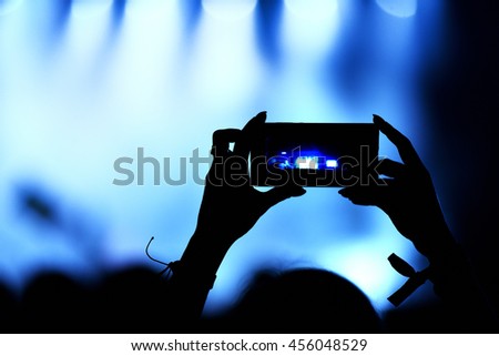 Person capturing a video on a mobile phone at a music festival
