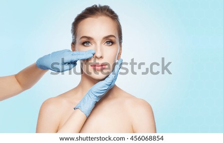 people, cosmetology, plastic surgery and beauty concept - surgeon or beautician hands touching woman face over blue background Royalty-Free Stock Photo #456068854