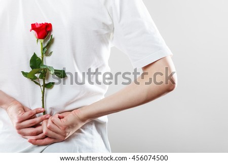 Anniversary proposal and engagement idea. Part body man with one red rose behind back. Love concept.
