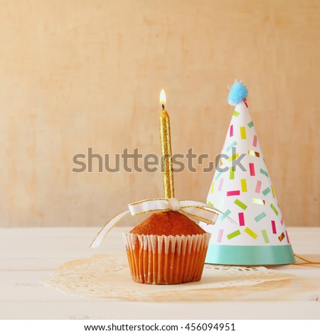 Birthday concept with cupcake and candle, party hat on wooden table