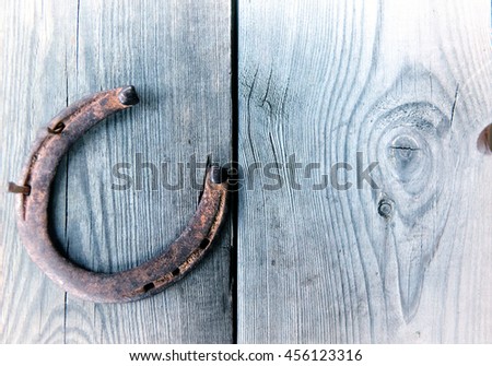  Rusty horseshoe on vintage wooden board - rustic scene in country style. Old iron Horseshoe - good luck symbol and mascot of well-being in village house in Western culture.