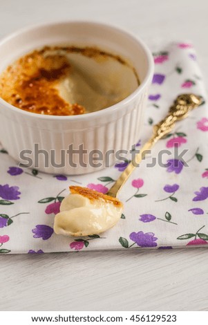 Ramekin with creme brulee and spoon in the middle.