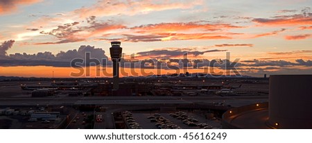 Airport at sunset with lit city skyline.