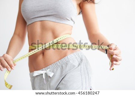 Woman measuring her waistline. Closeup of female with perfect slim body and torso. Healthy nutrition and weight losing concept. Royalty-Free Stock Photo #456180247