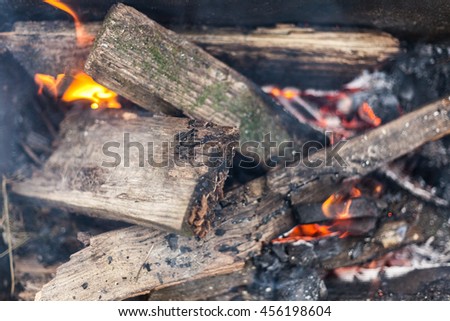 Burning in the fire board. Bonfire with flame, smoke, wooden planks and charcoals embers. Photo close-up with selective focus and blurred background