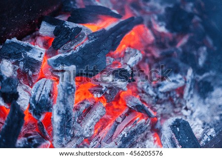 Red warm black coal char background texture. Blazing charcoal with fire, smoke. Photo for bonfire, bbq, dish skewers with selective focus